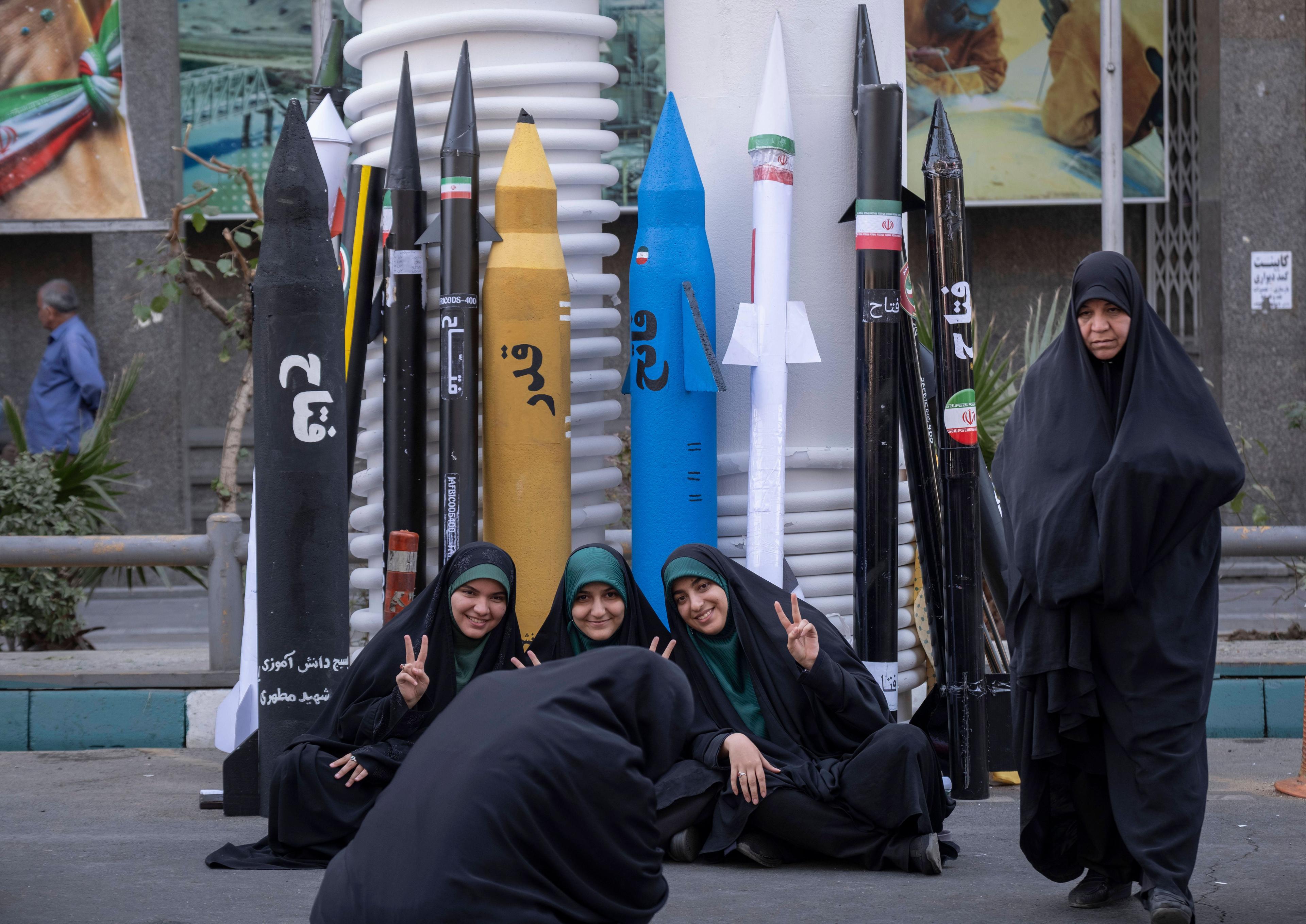 Frauen zeigen das Victory-Zeichen, während sie vor Modellen ballistischer Raketen sitzen bei einer Kundgebung in Teheran, 4. November 2025.