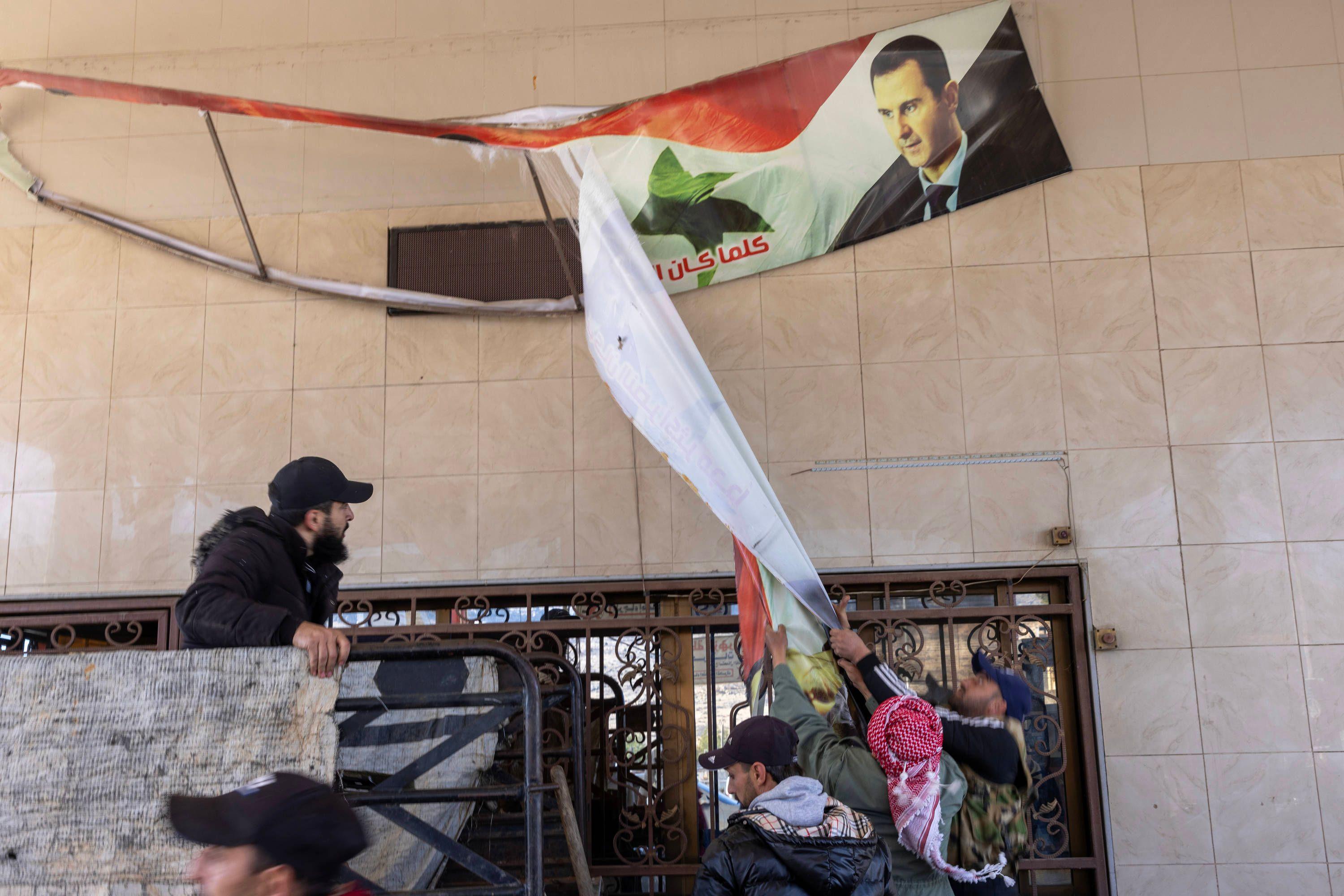 Anwohner reißen ein Bild des ehemaligen syrischen Präsidenten Baschar al-Assad am syrisch-libanesischen Grenzübergang in der Nähe von Jdaidit Yabws, Syrien, herunter, 9. Dezember 2024.