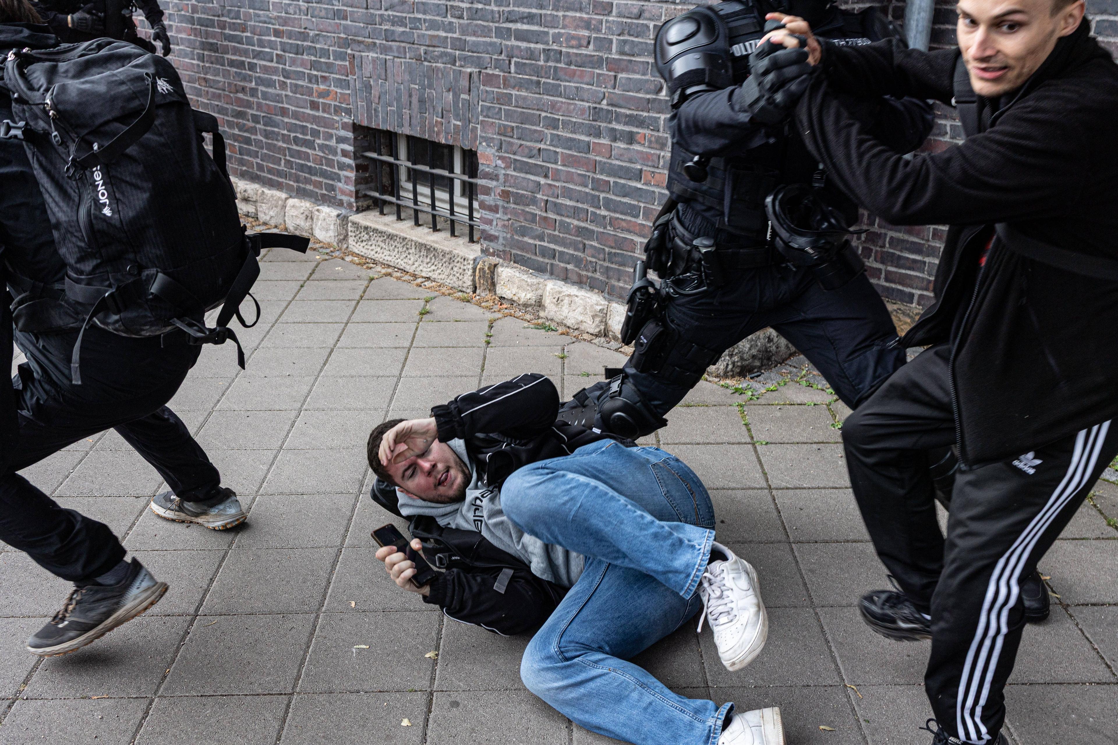 Polizisten versuchen, einen Journalisten von Apollo News zu schützen, während Proteste gegen den Bundesparteitag der AfD in Erfurt, 4. Juli 2026.