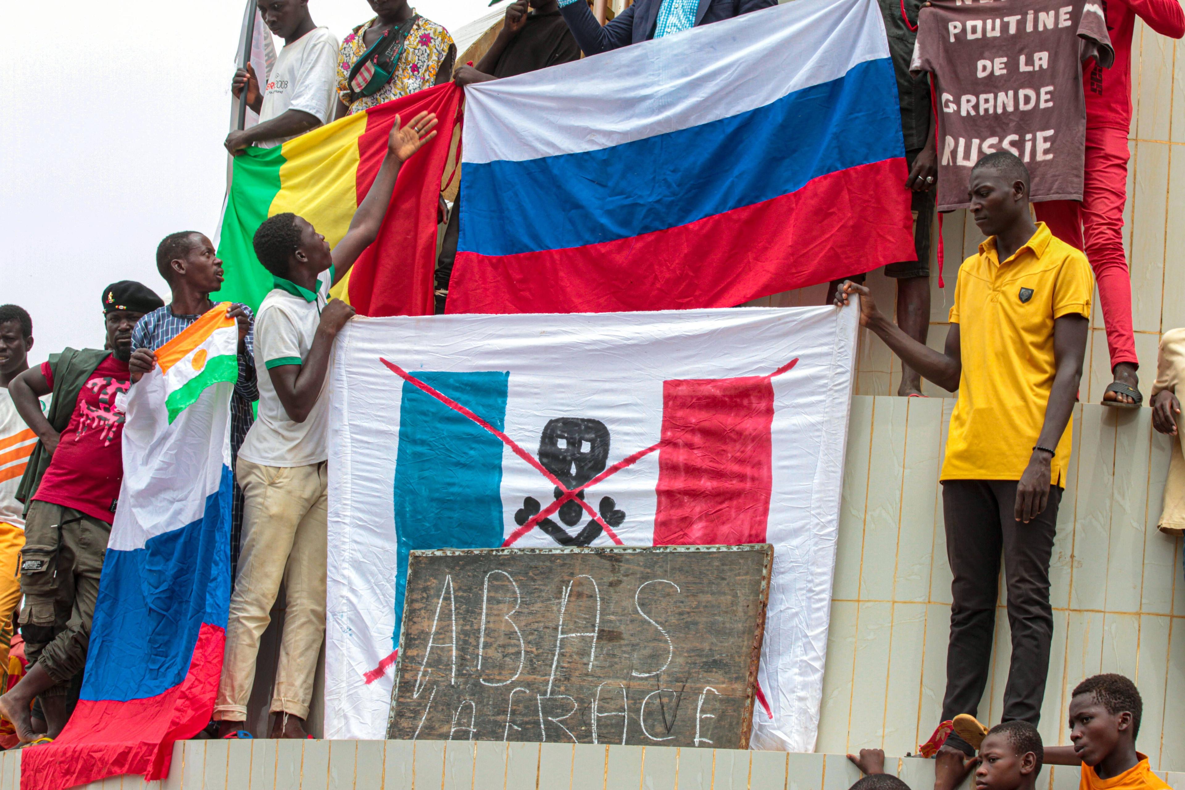 Demonstrierende in Niamey zeigen Flagge unweit der nigrischen Nationalversammlung und der französischen Botschaft.